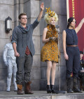 Peeta (Josh Hutcherson), Effie (Elizabeth Banks) e Katniss (Jennifer Lawrence) em Jogos Vorazes: Em Chamas